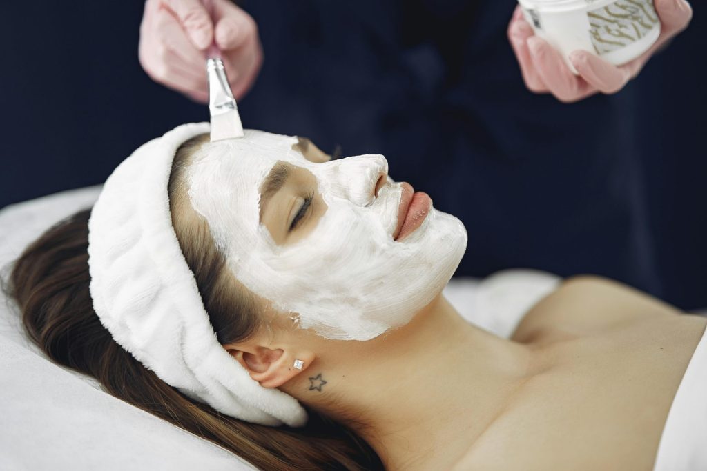 Gros plan sur une femme aux yeux fermés profitant d'un masque facial apaisant dans un spa.